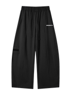 MONUMENTS structured wide-leg sweatpants in black heavyweight fleece with elastic waistband, extended drawcord and MNMNTS hip print, front view.