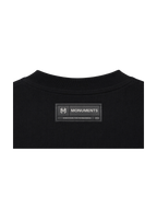 Woven MONUMENTS back-neck label on the black MM core logo boxy tee.