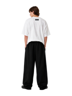 Model wearing the white MONUMENTS 414 Structure oversized tee with black wide-leg trousers, back view.