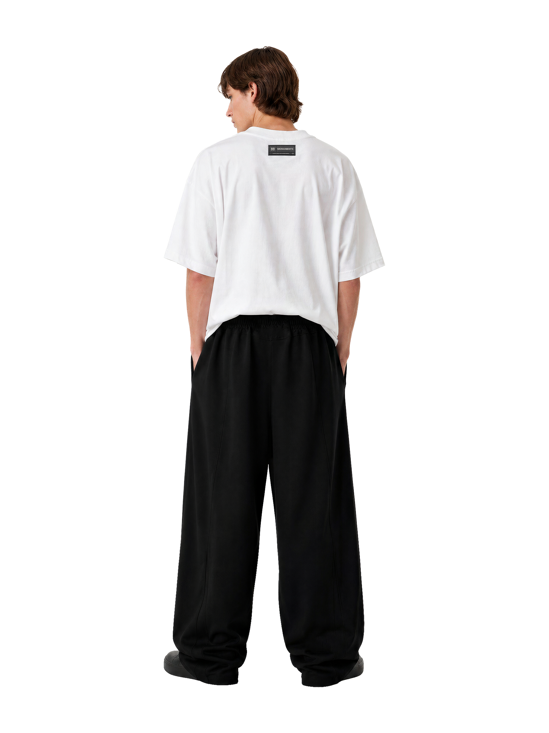 Model wearing the white MONUMENTS 414 Structure oversized tee with black wide-leg trousers, back view.