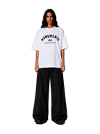 Model wearing the white MONUMENTS 414 Structure oversized tee with black wide-leg trousers, front view.